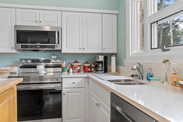 kitchen with light stone countertops, sink, white cabinets, and stainless steel appliances