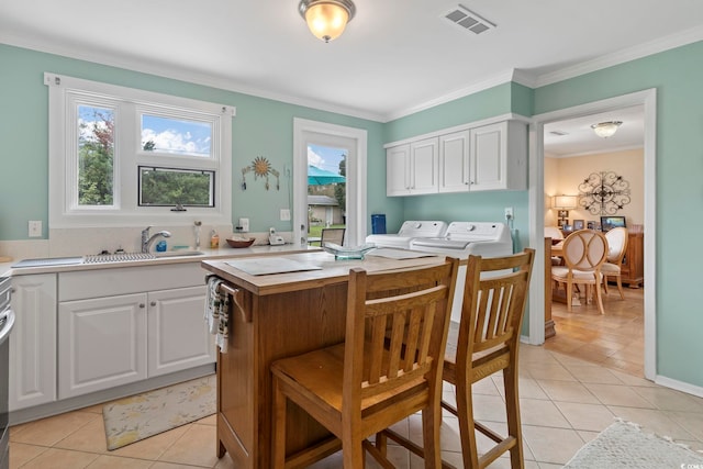 kitchen featuring ornamental molding, white cabinetry, sink, and washer and clothes dryer