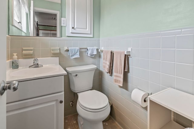 bathroom with toilet, vanity, and tile walls