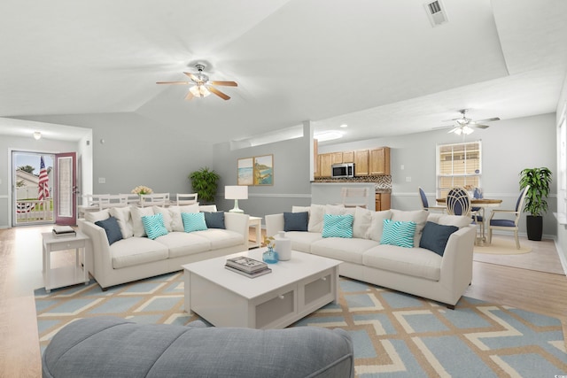 living room featuring ceiling fan, lofted ceiling, and light hardwood / wood-style flooring