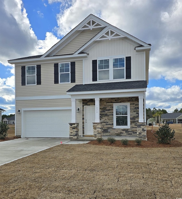 craftsman-style house with a garage, board and batten siding, a front lawn, and concrete driveway