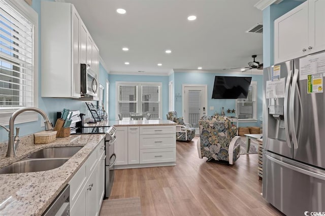 kitchen featuring light stone counters, sink, light hardwood / wood-style floors, white cabinetry, and appliances with stainless steel finishes