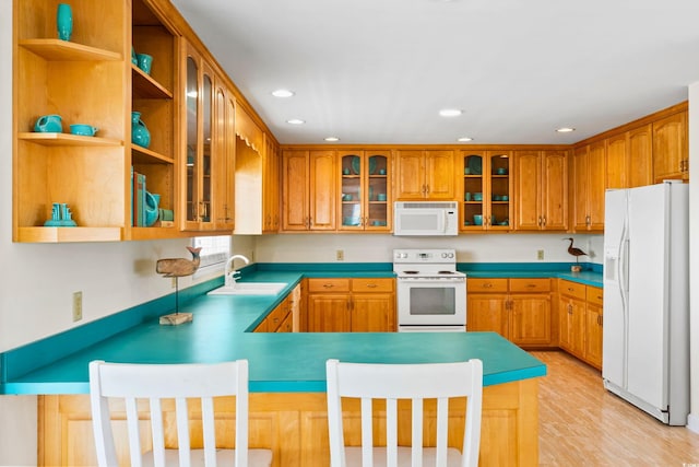 kitchen featuring sink, kitchen peninsula, light wood-type flooring, and white appliances