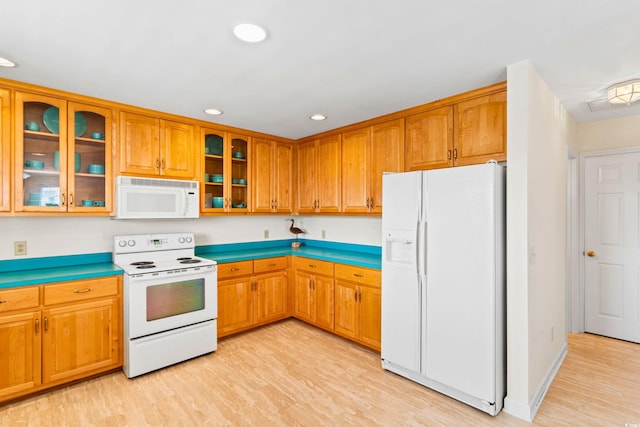 kitchen with white appliances and light hardwood / wood-style flooring