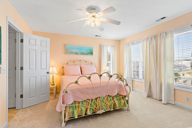 bedroom featuring light carpet, multiple windows, and ceiling fan