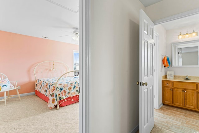 bedroom with light hardwood / wood-style flooring, ceiling fan, and sink