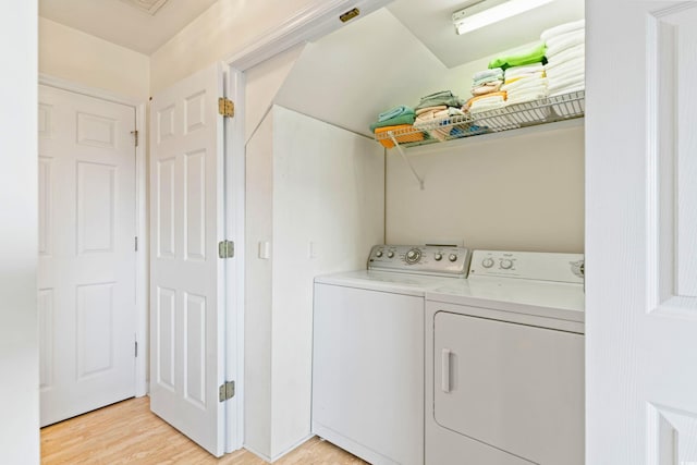 clothes washing area with washing machine and dryer and light wood-type flooring