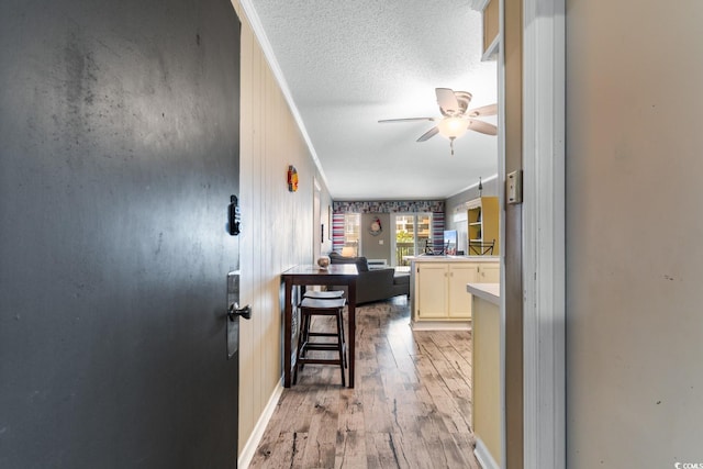 kitchen featuring a textured ceiling, kitchen peninsula, light hardwood / wood-style floors, ceiling fan, and a breakfast bar