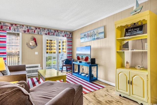 living room featuring ornamental molding, a textured ceiling, light wood-type flooring, and a wall unit AC