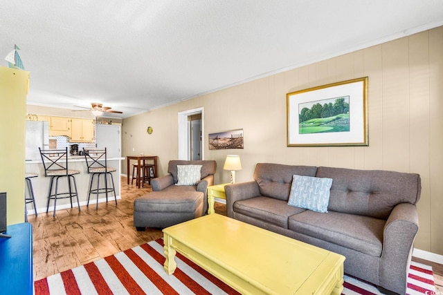 living room with light hardwood / wood-style floors, crown molding, and ceiling fan