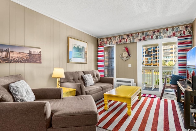 living room featuring a wall mounted air conditioner, wood walls, ornamental molding, and a textured ceiling