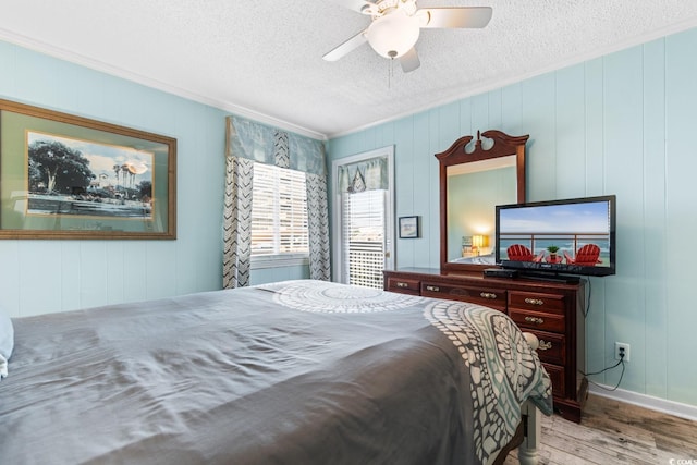 bedroom featuring ceiling fan, a textured ceiling, light hardwood / wood-style flooring, and wooden walls