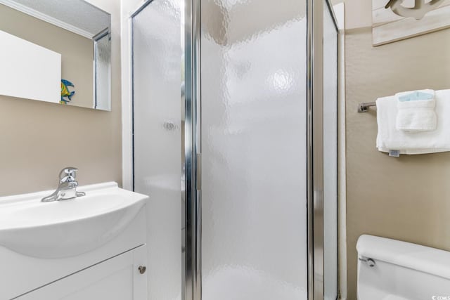 bathroom with toilet, ornamental molding, walk in shower, and vanity