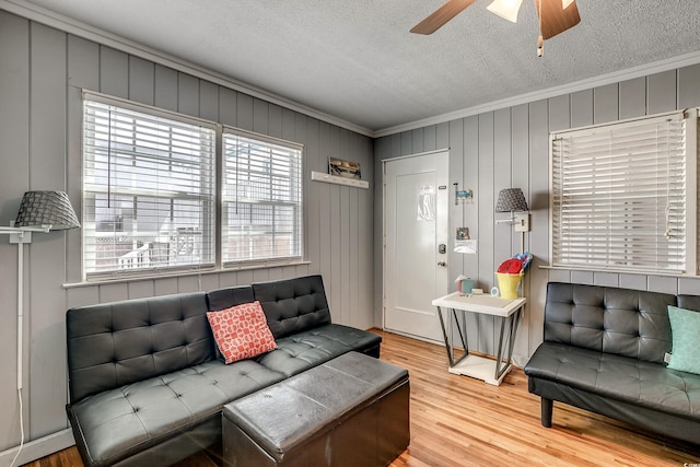 living room featuring wood-type flooring, a textured ceiling, ceiling fan, and crown molding