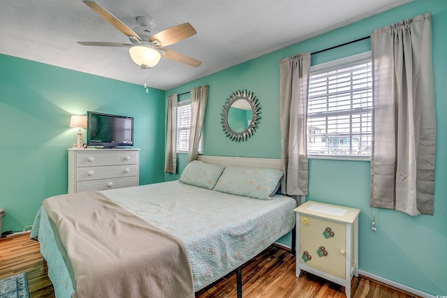 bedroom featuring a textured ceiling, light hardwood / wood-style flooring, multiple windows, and ceiling fan