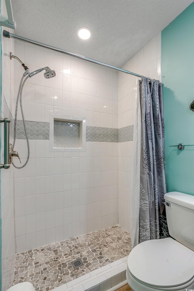 bathroom featuring a shower with shower curtain, a textured ceiling, and toilet