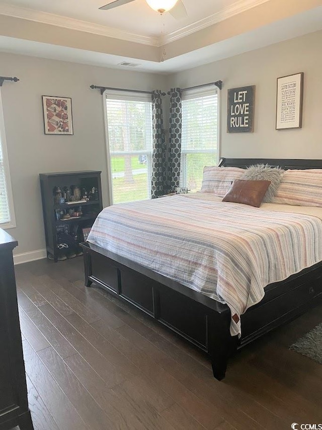 bedroom featuring ornamental molding, ceiling fan, dark hardwood / wood-style flooring, and a tray ceiling