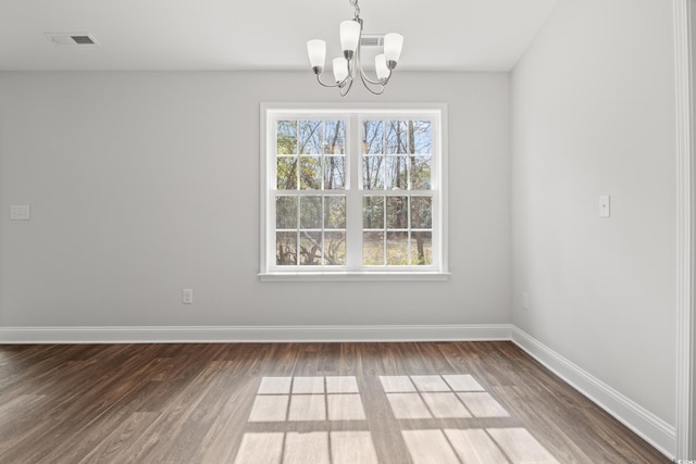 unfurnished dining area with a notable chandelier, visible vents, baseboards, and wood finished floors