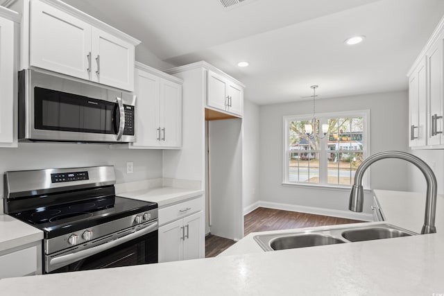 kitchen with appliances with stainless steel finishes, light countertops, white cabinets, and a sink