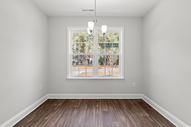 unfurnished dining area with dark wood-style floors, baseboards, and a notable chandelier