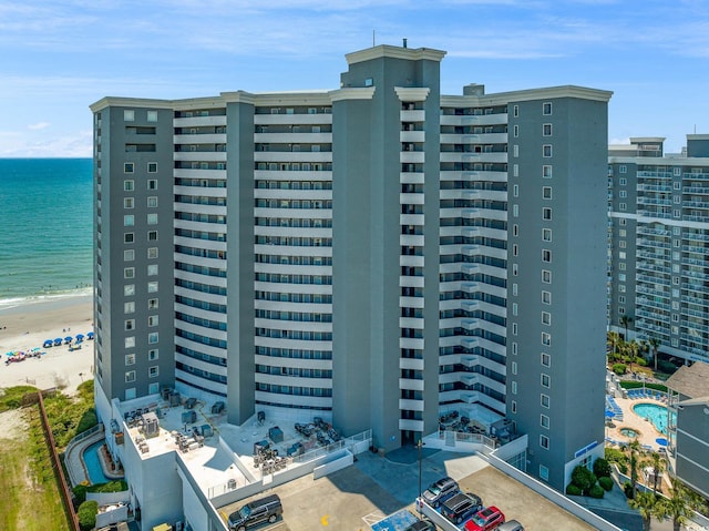 view of building exterior featuring a water view and a view of the beach