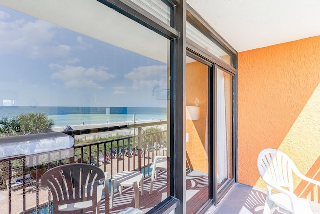 balcony with a water view and a view of the beach