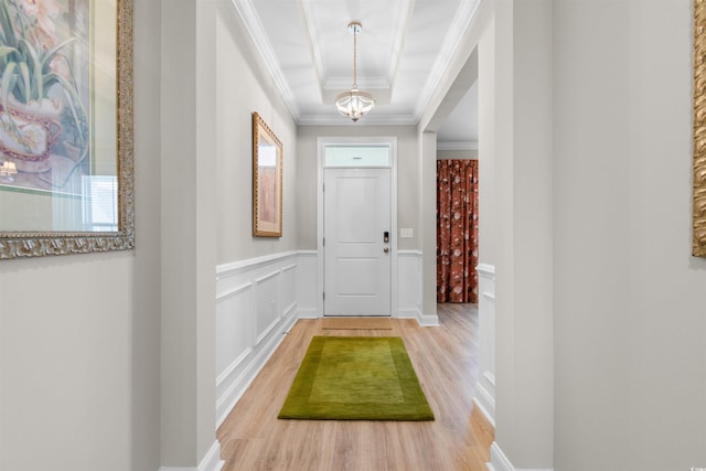 hallway with hardwood / wood-style flooring, a tray ceiling, crown molding, and plenty of natural light