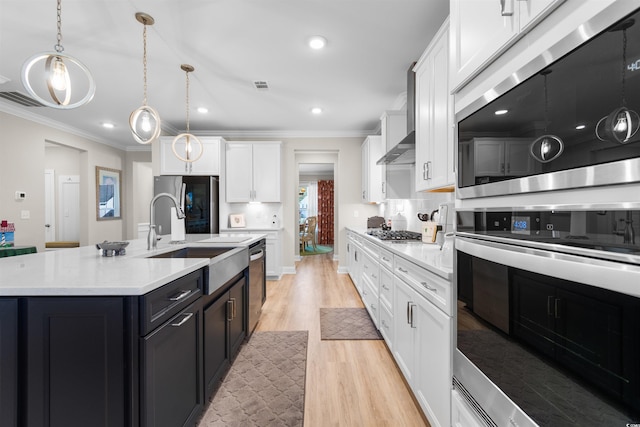 kitchen with hanging light fixtures, sink, light hardwood / wood-style flooring, a center island with sink, and white cabinetry