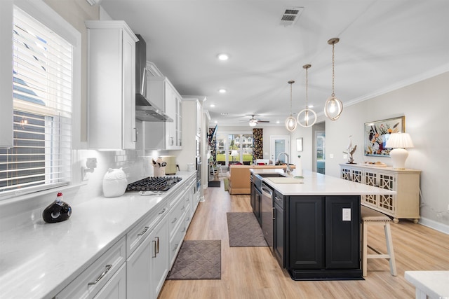 kitchen featuring a center island with sink, decorative light fixtures, appliances with stainless steel finishes, and white cabinetry