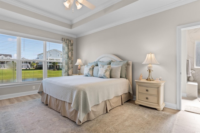 bedroom featuring ceiling fan, a raised ceiling, connected bathroom, light wood-type flooring, and crown molding