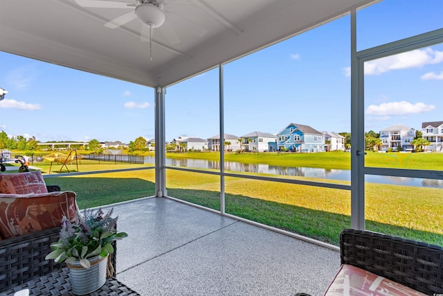 sunroom with ceiling fan and a water view