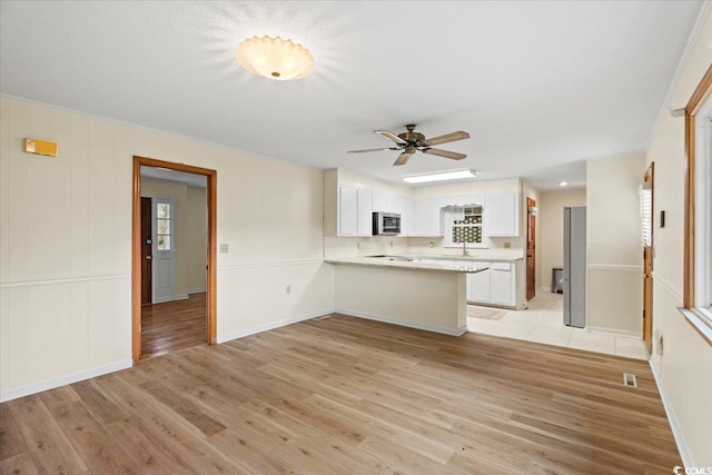 kitchen featuring light hardwood / wood-style floors, sink, white cabinetry, kitchen peninsula, and ceiling fan