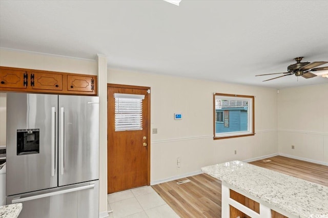 kitchen with light stone counters, light hardwood / wood-style floors, crown molding, ceiling fan, and stainless steel fridge