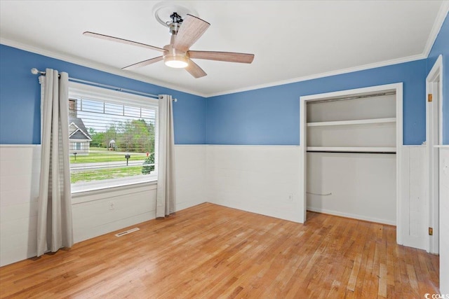 unfurnished bedroom featuring ceiling fan, a closet, light wood-type flooring, and crown molding