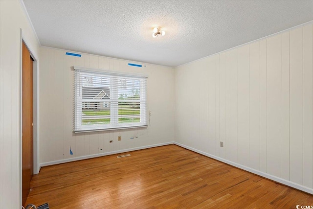 unfurnished room featuring wood-type flooring and a textured ceiling