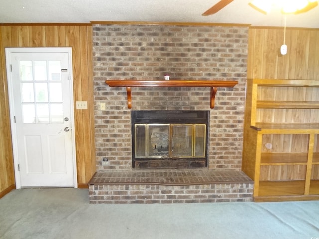 unfurnished living room with a fireplace, carpet floors, and wood walls