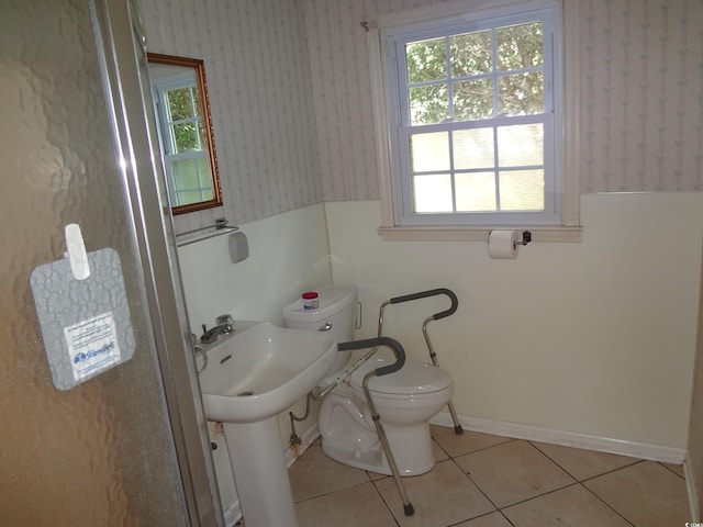 bathroom featuring tile patterned flooring, toilet, and a healthy amount of sunlight