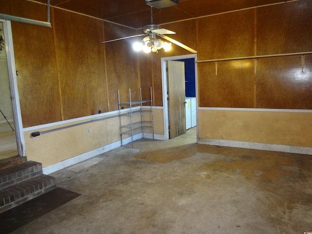 basement with ceiling fan and wooden walls