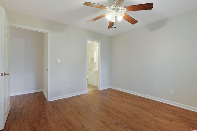 unfurnished bedroom with ceiling fan, ensuite bathroom, and dark wood-type flooring