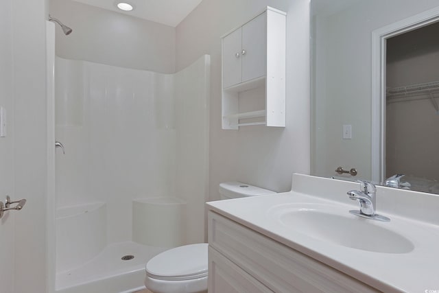 bathroom featuring walk in shower, vanity, and toilet