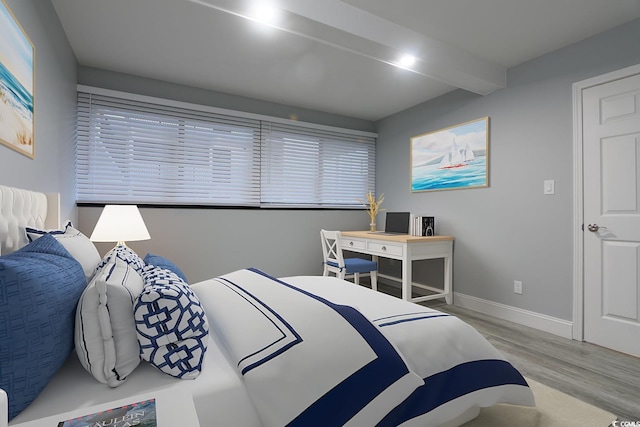 bedroom with beamed ceiling and light wood-type flooring