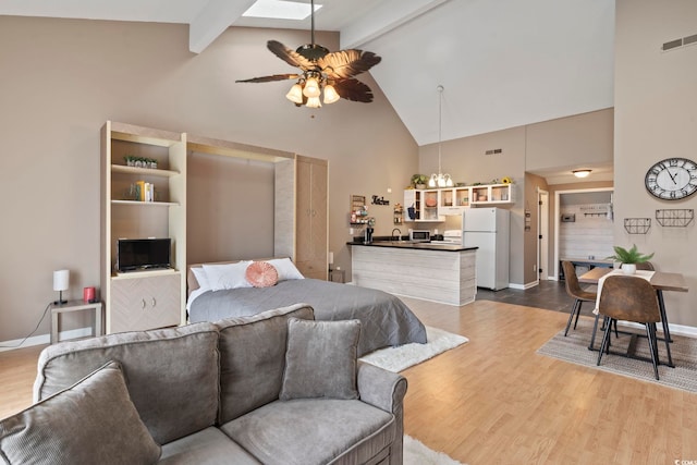 bedroom featuring white refrigerator, beam ceiling, high vaulted ceiling, a skylight, and hardwood / wood-style floors