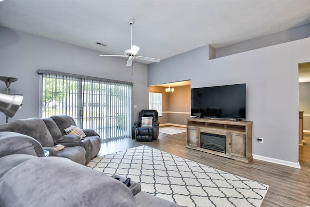 living room featuring ceiling fan with notable chandelier and hardwood / wood-style flooring