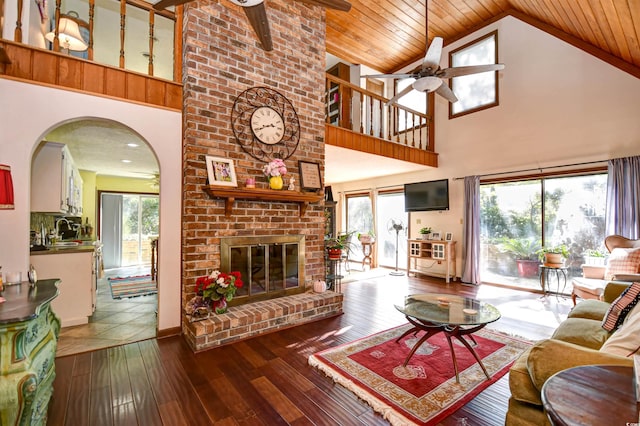 living room featuring wooden ceiling, dark wood-type flooring, a brick fireplace, and plenty of natural light