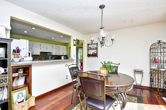 dining area featuring an inviting chandelier, dark wood-type flooring, and a textured ceiling