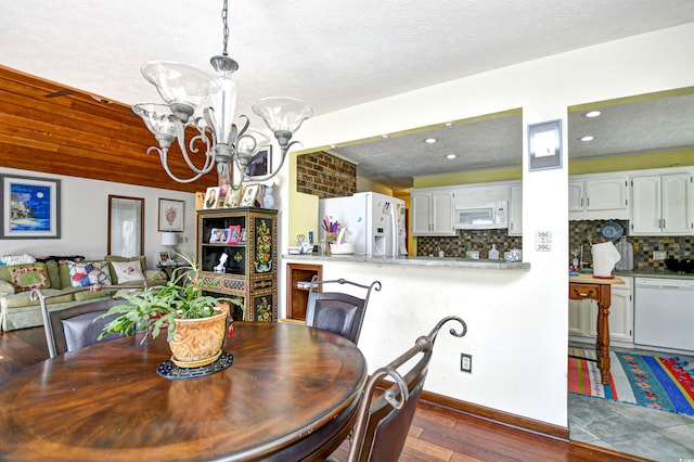 dining room with a chandelier, a textured ceiling, and dark wood-type flooring