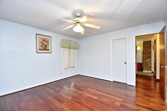 unfurnished room with a textured ceiling, dark hardwood / wood-style floors, and ceiling fan