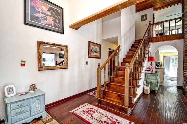 stairs with wood-type flooring and a high ceiling