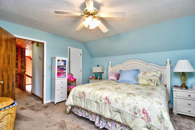 carpeted bedroom featuring a textured ceiling, vaulted ceiling, and ceiling fan