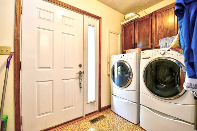 laundry area featuring a textured ceiling, independent washer and dryer, and cabinets